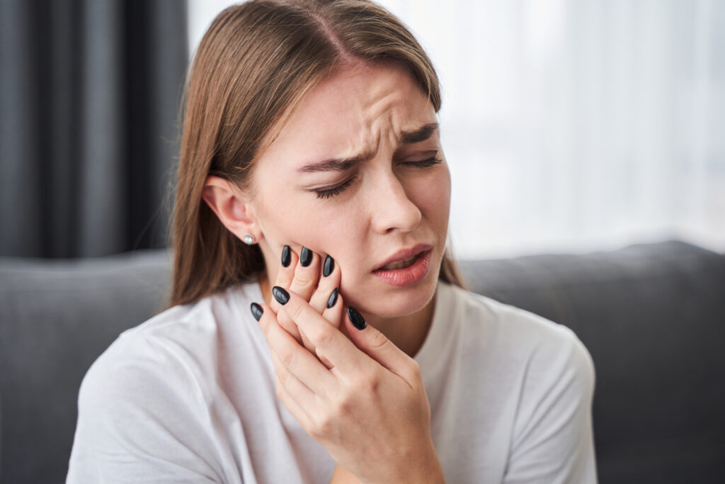 young woman suffering from head and jaw pain related to TMJ
