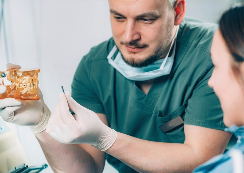 Dentist explaining the pros and cons of dental implants using a jaw model during a patient consultation