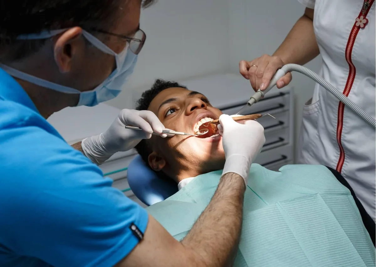 Dentist examining a patient&rsquo;s mouth to assess healing and determine when a dental implant can be placed after tooth extraction.