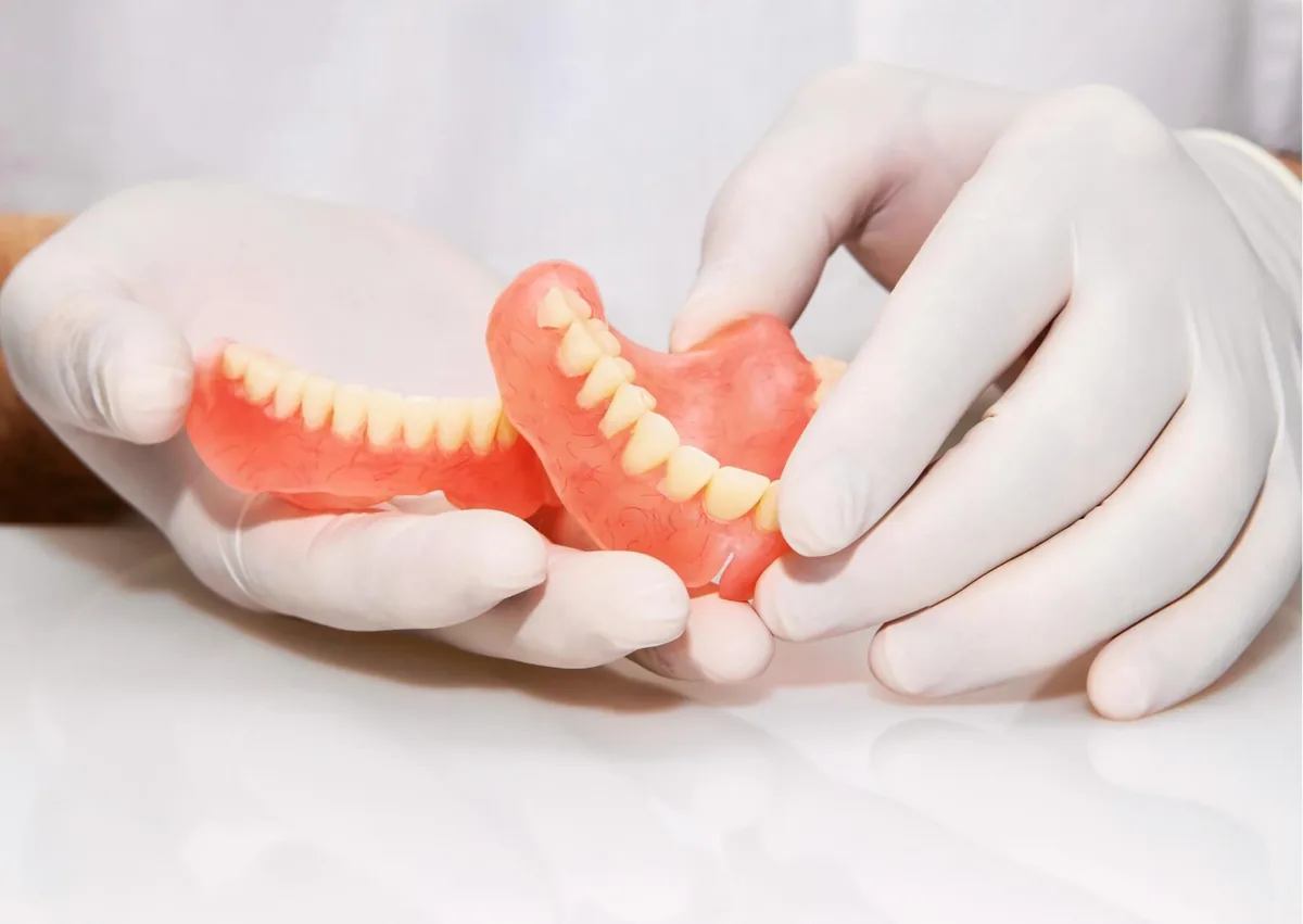 Dental professional examining removable dentures as part of evaluating their fit, condition, and lifespan.