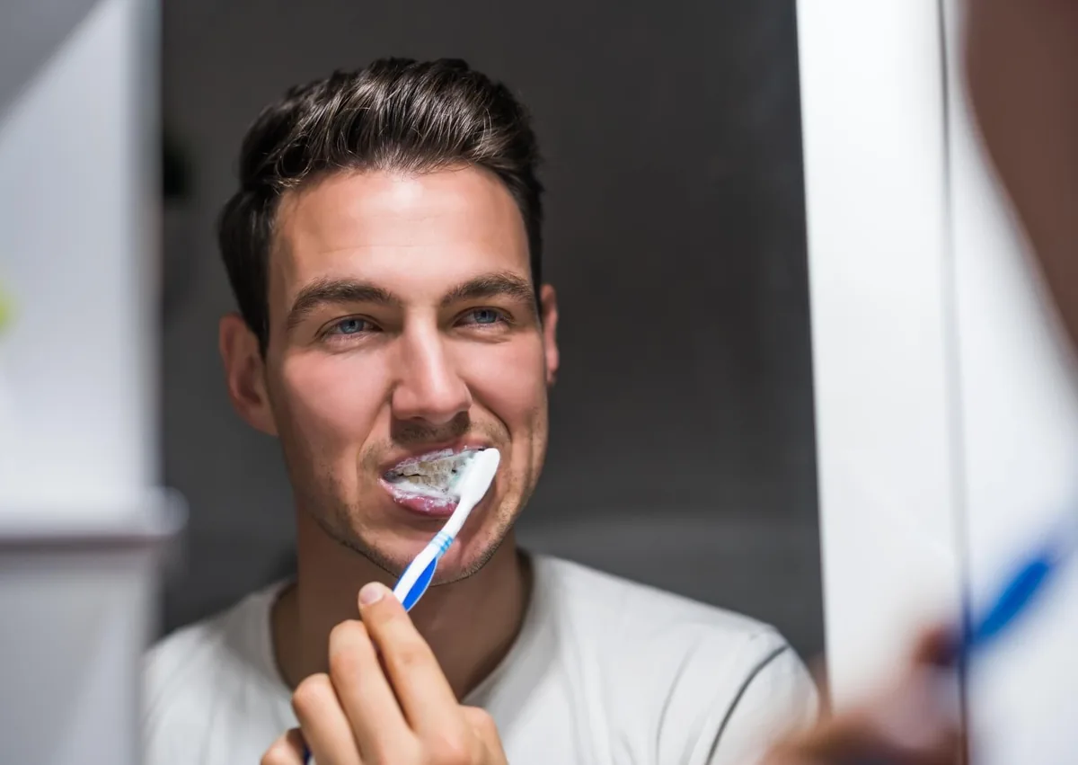 Man brushing his teeth to maintain oral hygiene and support a longer dental implant lifespan.