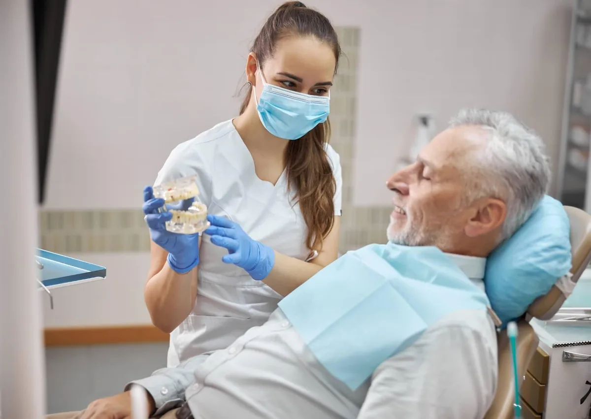 Dental professional discussing implant complications with an older patient concerned about possible dental implant failure.
